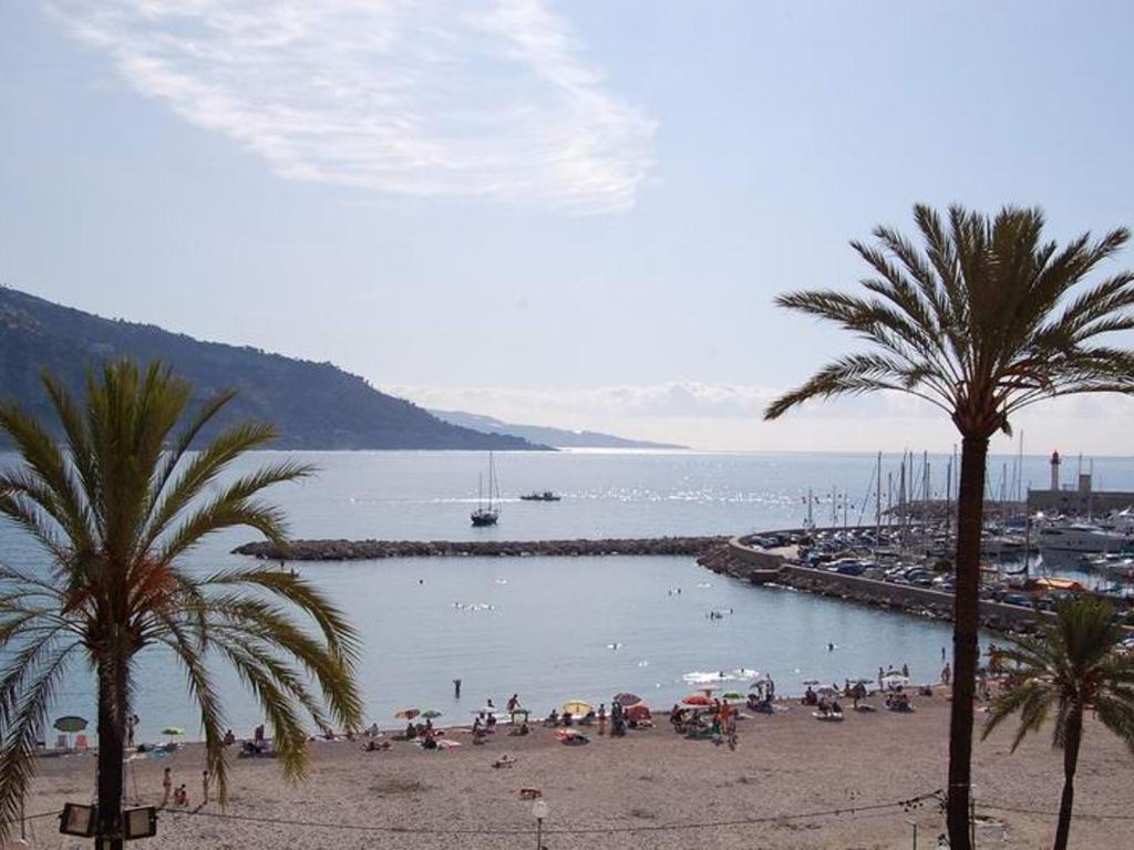 une plage avec des palmiers et un groupe de personnes dans l'établissement Charmant 2 pièces, vieille ville, proche plage - FR-1-196-195, à Menton