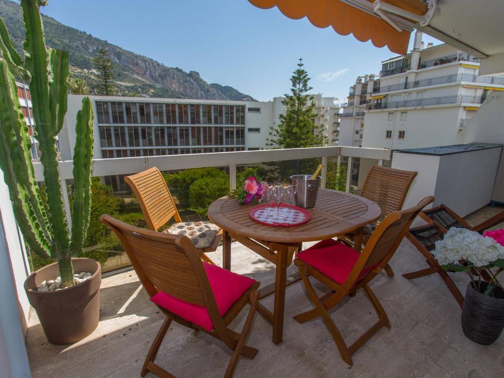 une table et des chaises en bois sur un balcon dans l'établissement Grand 2P avec Parking et Terrasse, Piscine sur le Toit, Proche des Plages à Menton - FR-1-196-172, à Menton