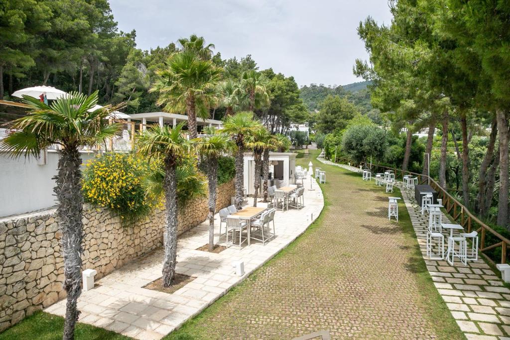 a garden with chairs and tables and a wall at AH Premium Baia dei Faraglioni in Mattinata