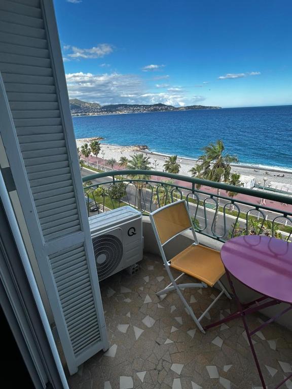 - un balcon avec une table, une chaise et la plage dans l'établissement Sea Front View - FRONT DE MER ET VUE PANORAMIQUE, à Nice