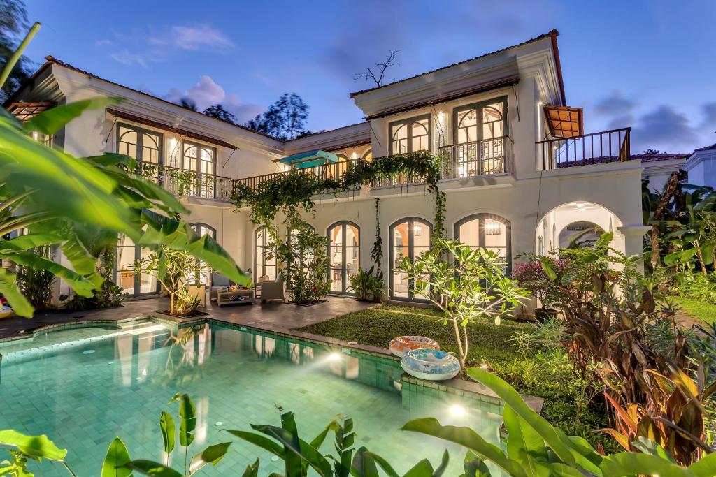 an exterior view of a mansion with a swimming pool at La Pasado, Huge 4 BHK villa with Large Private Pool & Garden, in Assagao, Complimentary Breakfast, full time caretaker, Bathtub, ideal for large groups in Assagao