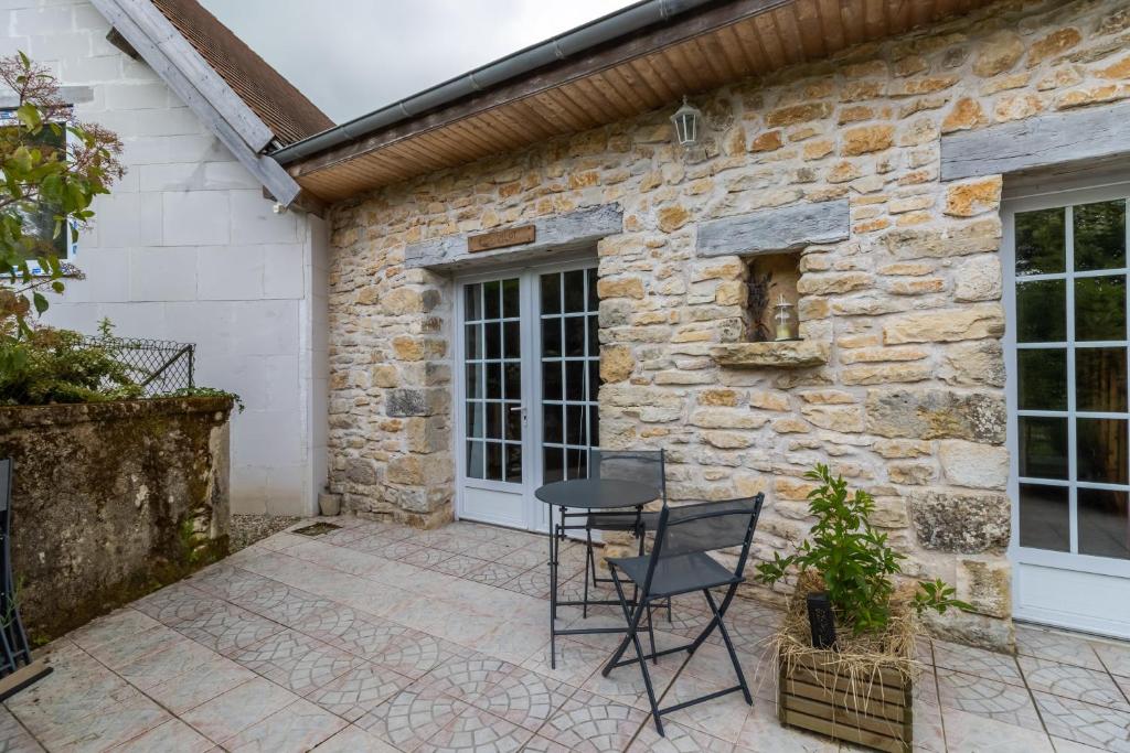un patio con tavolo e sedie di fronte a un edificio in pietra di Chambre Coquelicot ad Auriac-du-Périgord