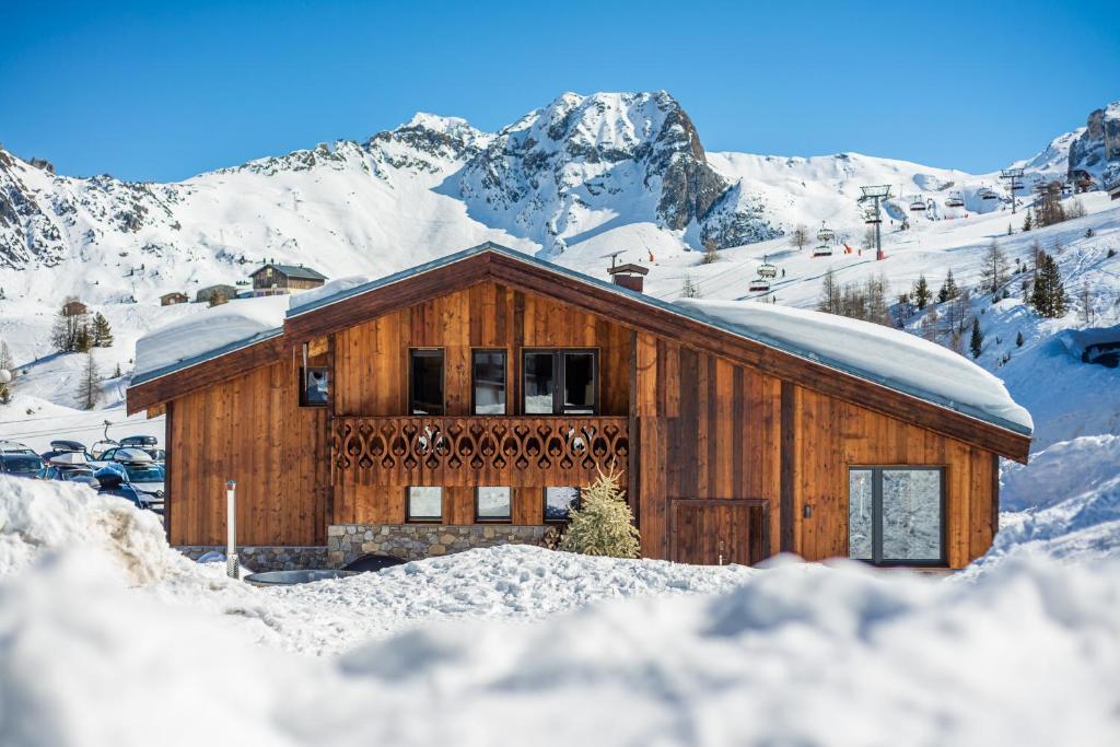 a wooden house in the snow with mountains in the background at Chalet RIVA ski in-out Plagne Village in La Plagne Tarentaise