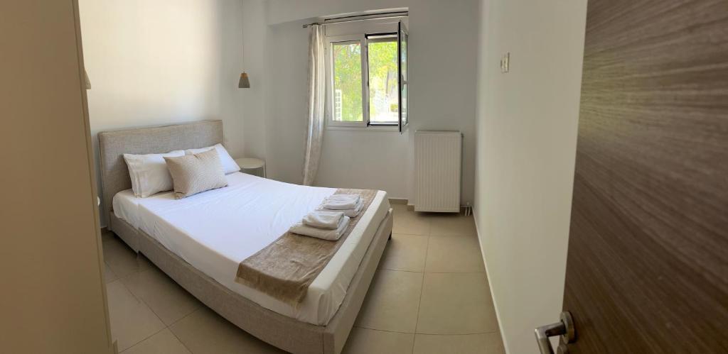 een slaapkamer met een bed met witte lakens en een raam bij Ammouses Apartment in Potamós