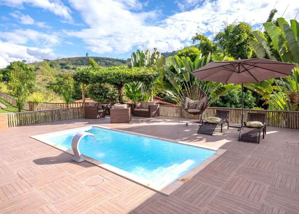 a swimming pool with an umbrella on a patio at Otima Chacara com lazer completo, pet friendly in Carmo