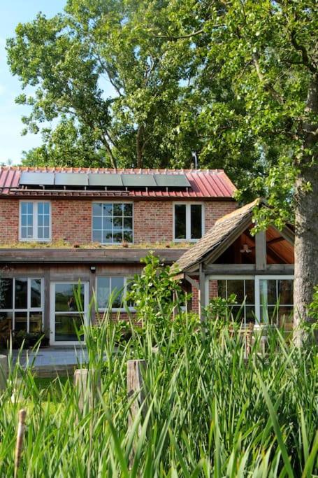 a brick house with a red roof and a tree at den overkant in Diksmuide