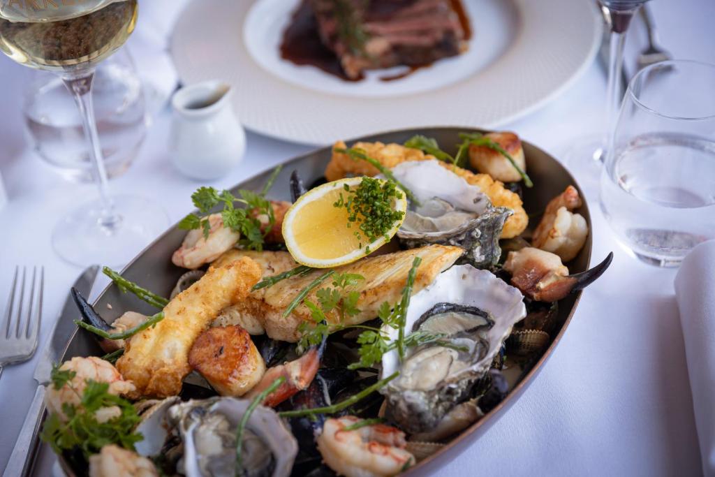 a plate of seafood on a table with a glass of wine at Glenroyal Hotel in Maynooth