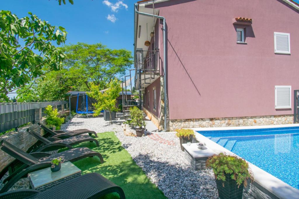 a backyard with a pool and a pink house at Koky in Juršići
