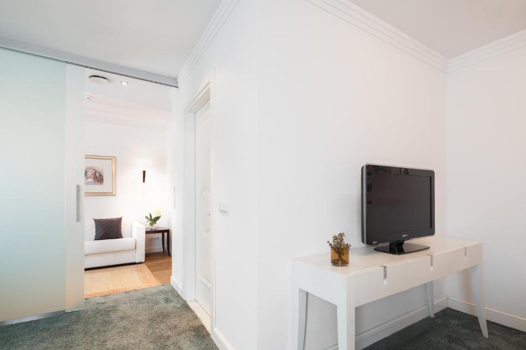 Biały salon z telewizorem na białym stole w obiekcie Hotel Europa Splendid w Meranie