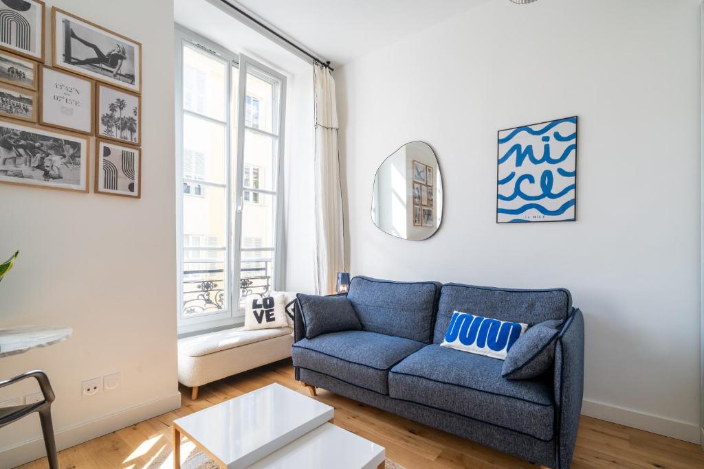 un salon avec un canapé bleu et une fenêtre dans l'établissement Studio lumineux Centre-ville, à Nice