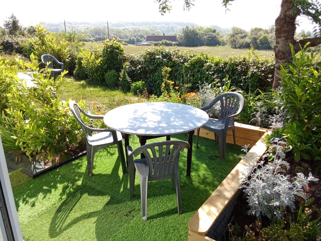 a table and chairs sitting on the grass in a garden at AU PETIT BONHEUR Chez l'habitant 2PERS in Ferques