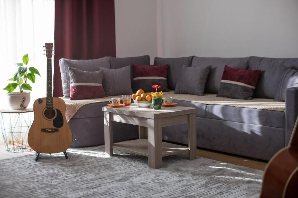 a living room with a couch and a table with a guitar at NIDA Apartment in Ulcinj