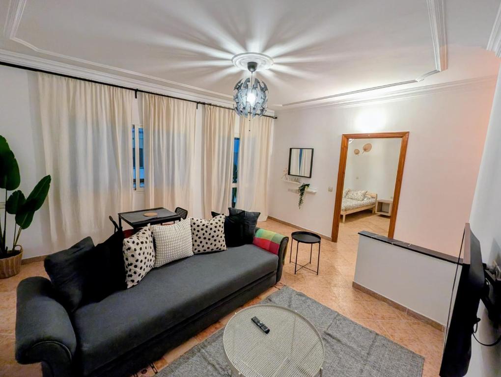 Una sala de estar con un sofá negro y un televisor. en City Escape Assilah 1, en Asilah