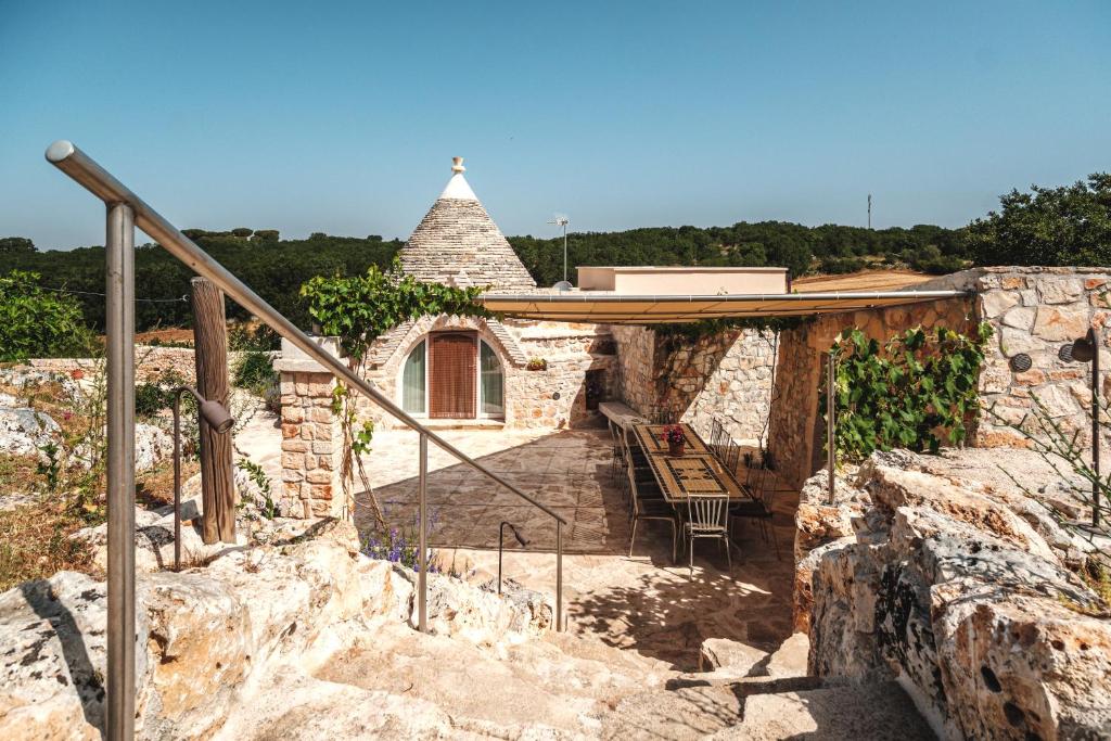 a stone house with a porch and a chair at HelloAPULIA Trulli Flora - Charming Trulli with Private Pool and Garden in Noci