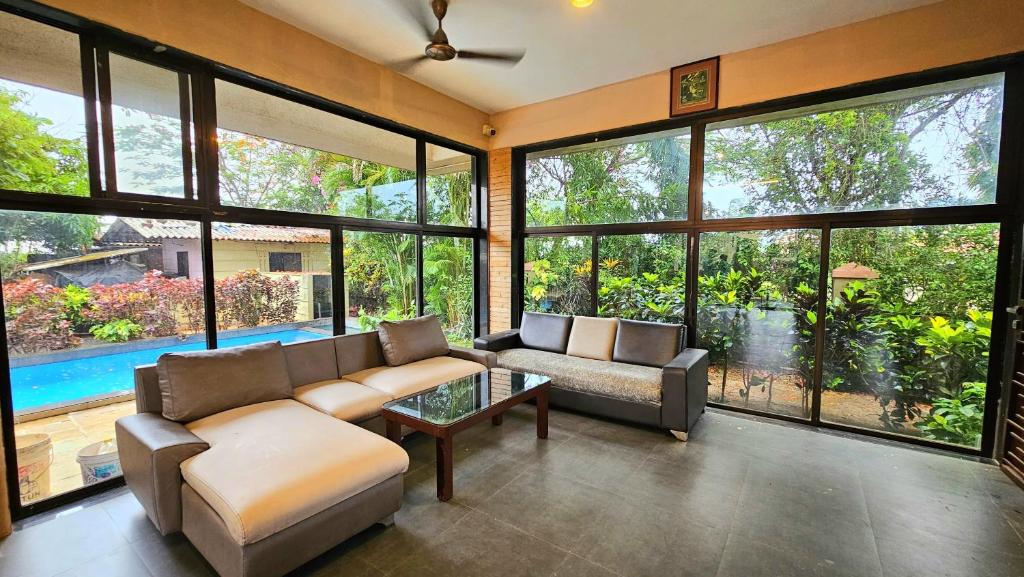 ein Wohnzimmer mit Sofa und Tisch in der Unterkunft Elephant House Luxury Villa with Curve Pool-Colossal Garden-Panoramic View in Lonavla