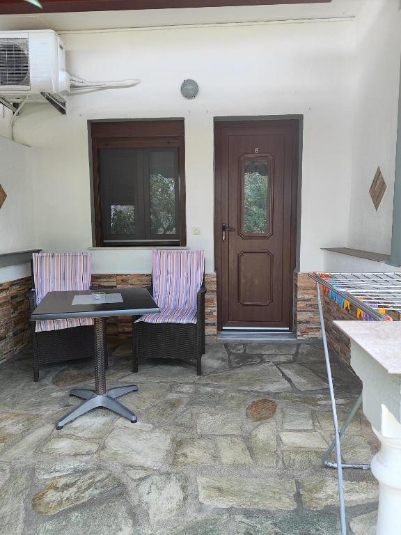 a patio with two chairs and a table and a door at Pelagos Beachfront in Panormos Skopelos
