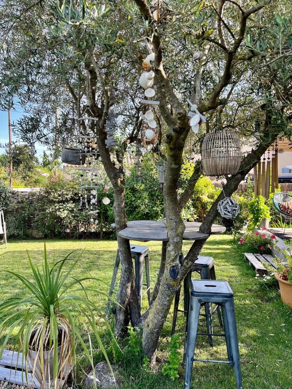 une table et deux tabourets à côté d'un arbre dans l'établissement villa dans un écrin de verdure, à Saint-Quentin-la-Poterie