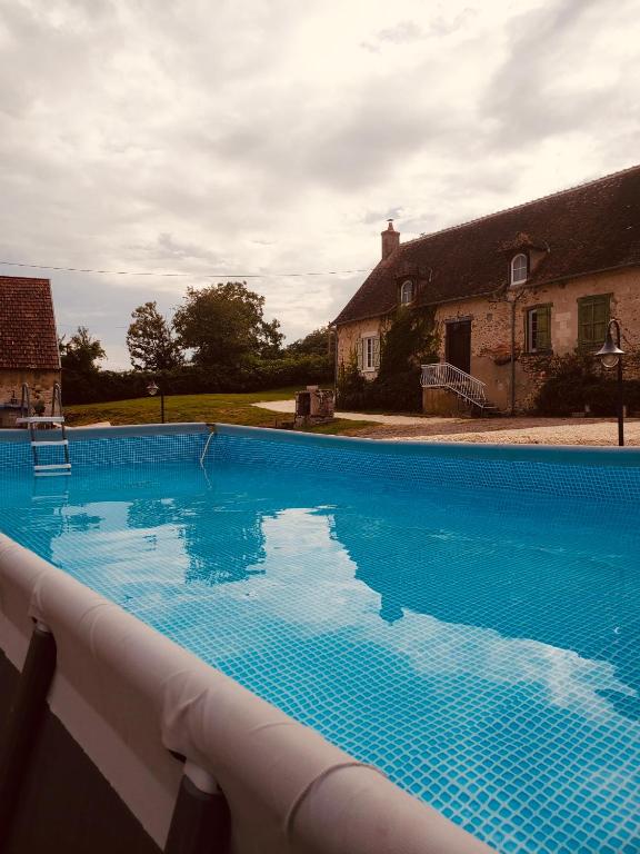 une grande piscine bleue devant une maison dans l'établissement Gîte de charme dans le Sancerrois, à Bannay