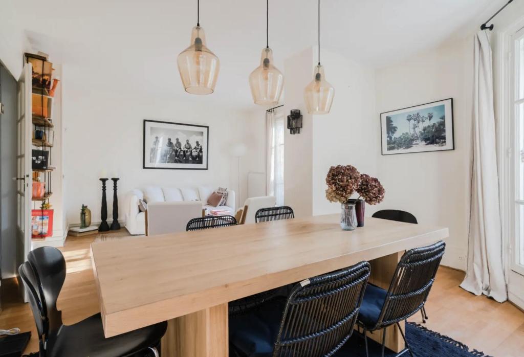 une salle à manger avec une table et des chaises en bois dans l'établissement Appartement parisien baigné de soleil, à Paris