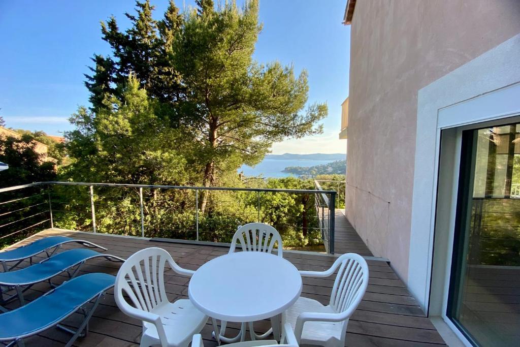 une table blanche et des chaises sur un balcon avec vue dans l'établissement Renovated 1-bedroom apartment with sea view and large balcony Aiguebelle, au Lavandou