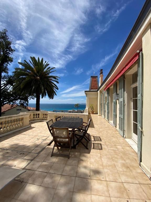 une table et des chaises sur une terrasse avec vue sur l'océan dans l'établissement PALMERAIE - Magnifique appartement d'époque avec Vue Mer 4 personnes avec terrasse Le Port Nice, à Nice