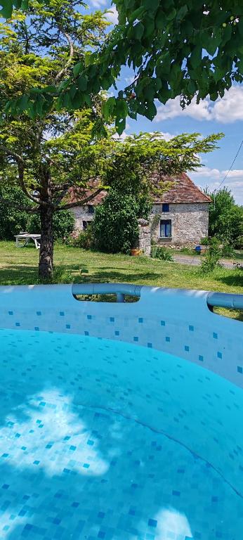 une piscine bleue avec une maison en arrière-plan dans l'établissement Gîte 4 pers, Jacuzzi, Piscine, proche Futuroscope, calme et nature à La Roche Posay, à La Roche-Posay