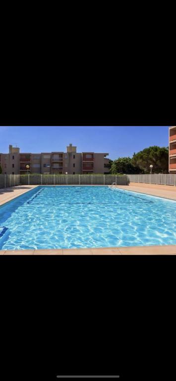 un grand bassin d'eau bleue avec des bâtiments en arrière-plan dans l'établissement Appartement Favière-plage, Piscine-Terrain de tennis-Foot, à Bormes-les-Mimosas