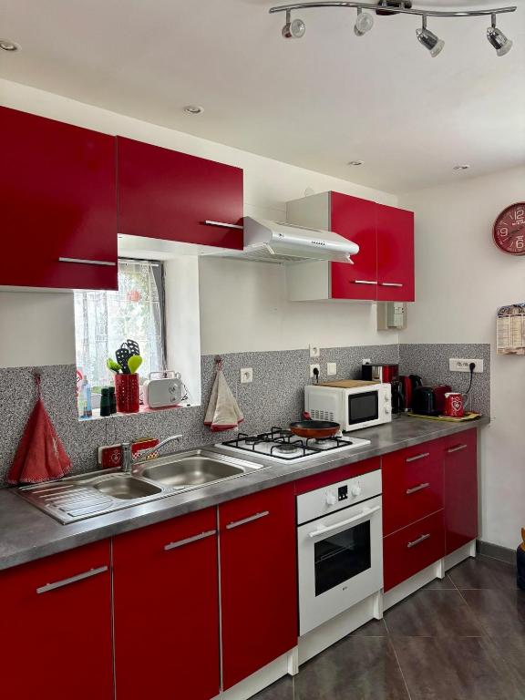 a kitchen with red cabinets and a sink at Maison à la campagne Les quatre vents in Saint-Martin-dʼAbbat