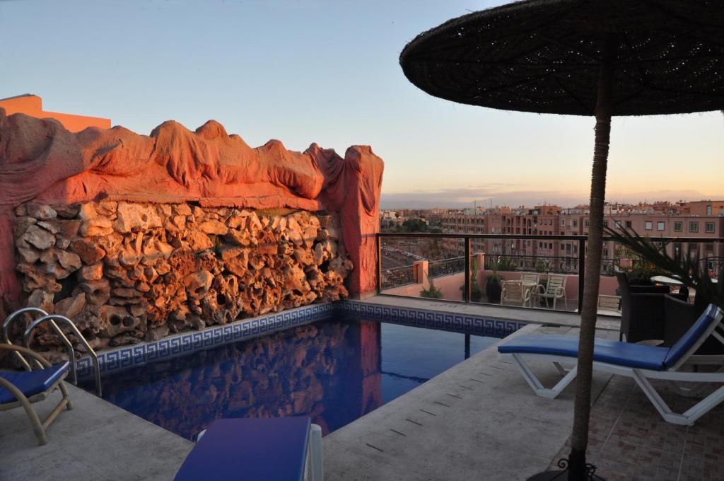 una piscina con un muro de piedra y una sombrilla en Mont Gueliz, en Marrakech
