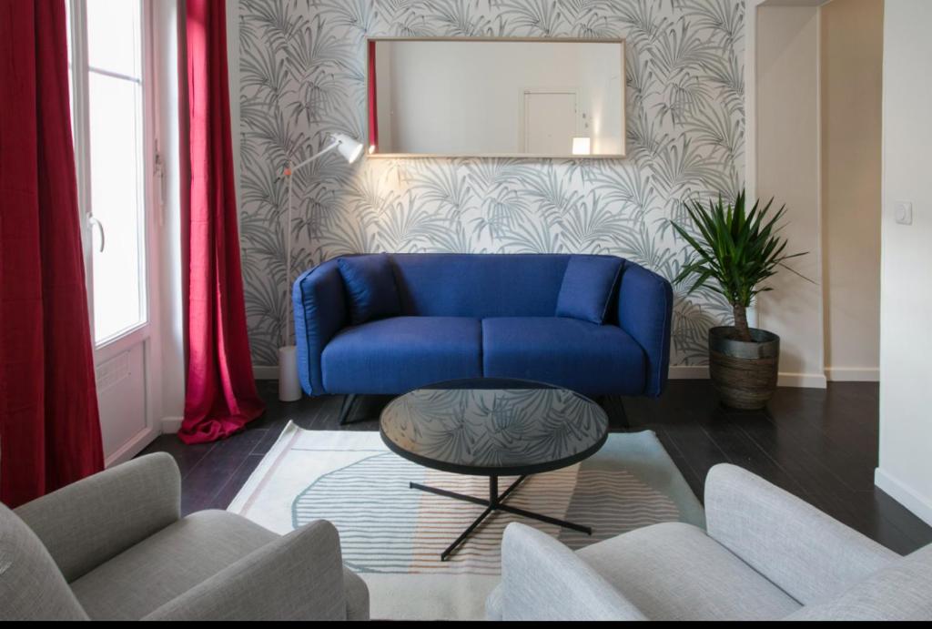 un canapé bleu dans un salon avec un miroir dans l'établissement Charmant Appartement au calme, à Levallois-Perret