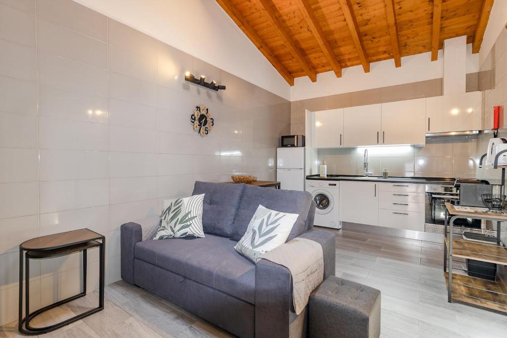 a living room with a blue couch and a kitchen at Cantinho da Deolinda in Luz