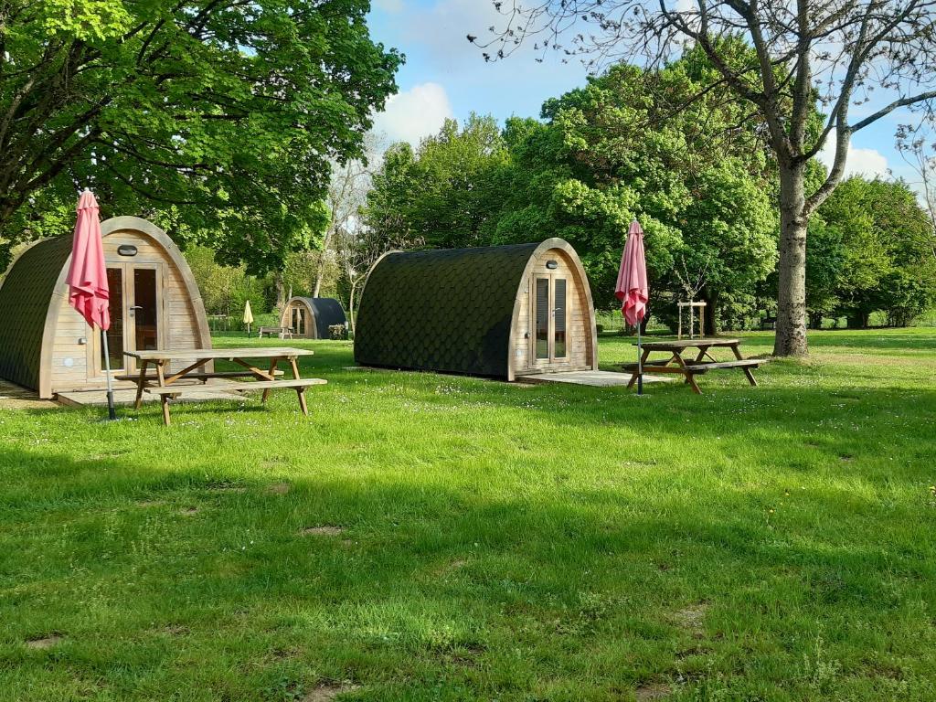 two picnic tables with umbrellas in a park at Camping Onlycamp Port Sainte Marie in Malicorne-sur-Sarthe