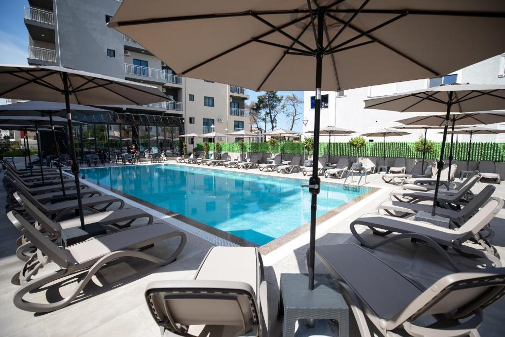 a swimming pool with lounge chairs and umbrellas at Hotel Apart Resilient in Golem