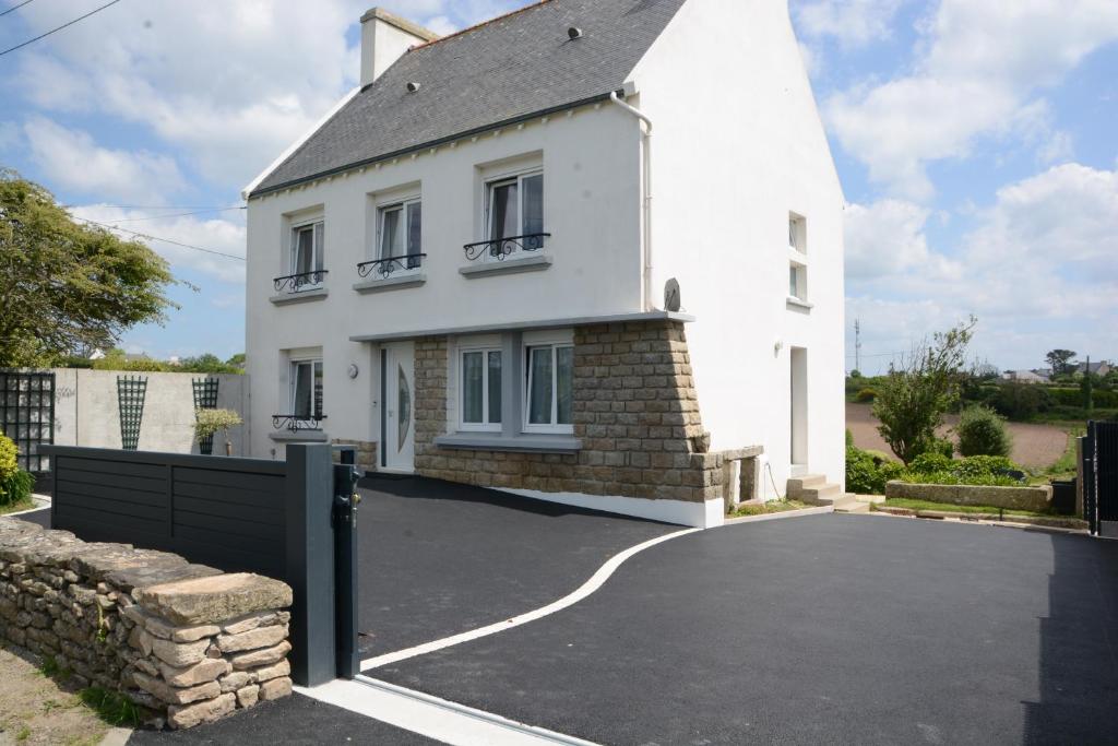 une maison blanche avec une porte noire et une allée. dans l'établissement IROISE GRANDE MAISON en Baie d'Audierne Finistère 5 chambres, à Plozévet