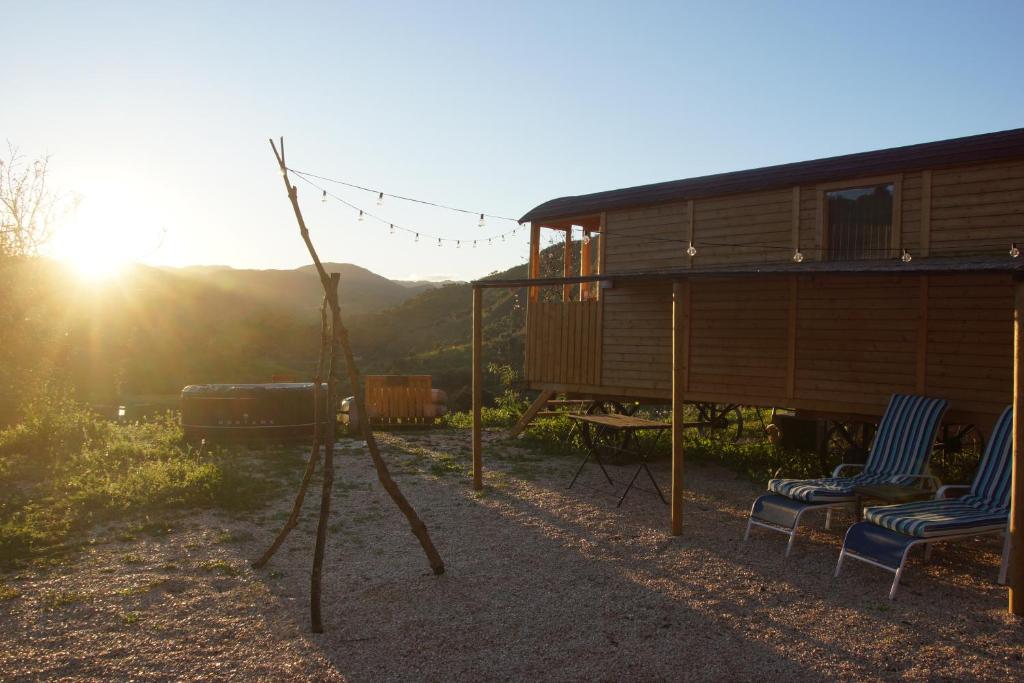 two chairs and a house with the sunset in the background at Finca la montaña roja in Almogía