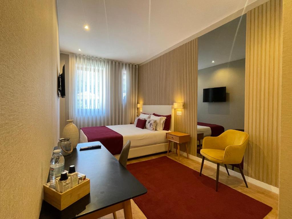 a hotel room with a bed and a table and chair at MyTrip Porto in Matosinhos