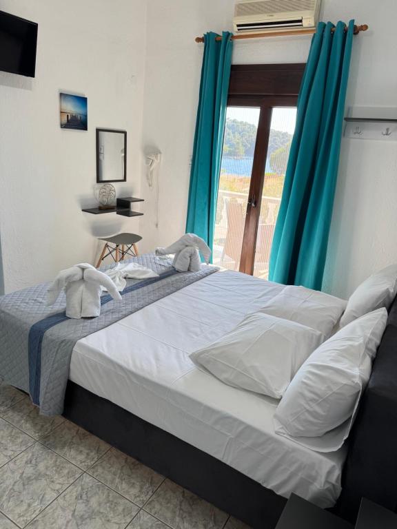 a bedroom with a large bed with blue curtains at Pelagos Beachfront in Panormos Skopelos