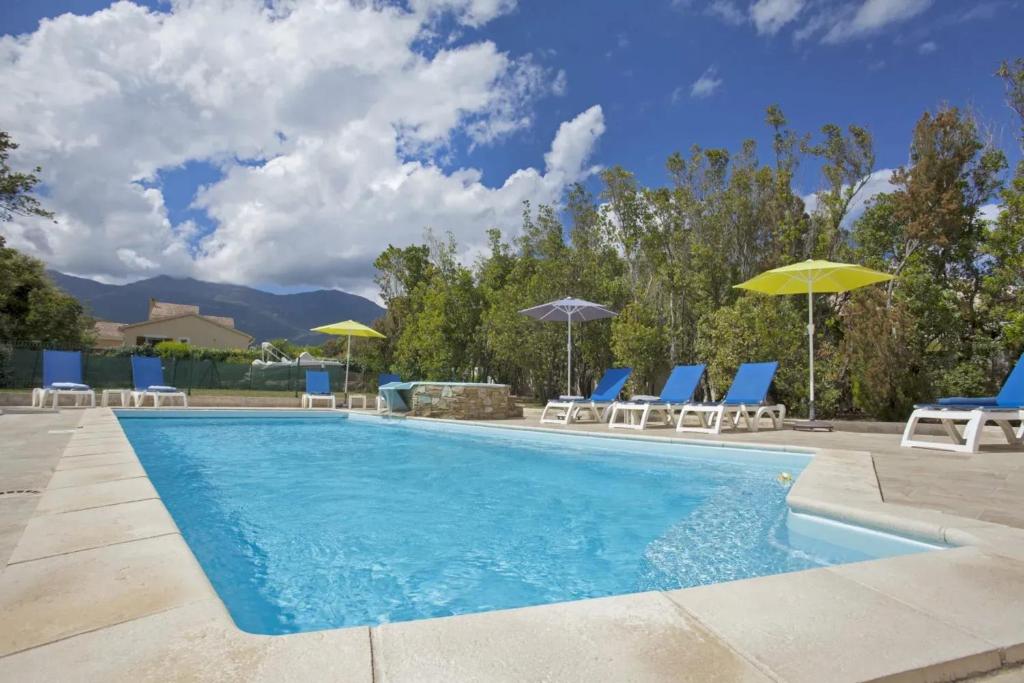 une piscine avec chaises et parasols dans l'établissement Maison cosy près de Pietracorbara avec piscine, à Pietracorbara