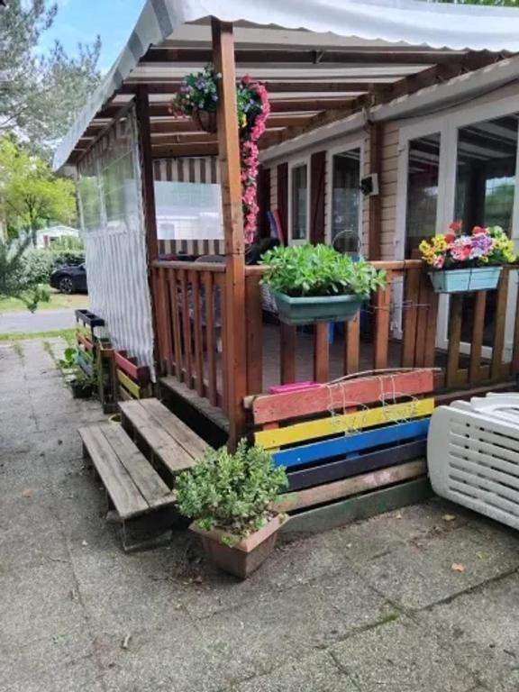 une maison colorée avec des plantes en pot sur le porche dans l'établissement Bungalow idéal à Saint-Jean-de-Monts avec piscine, à Saint-Jean-de-Monts