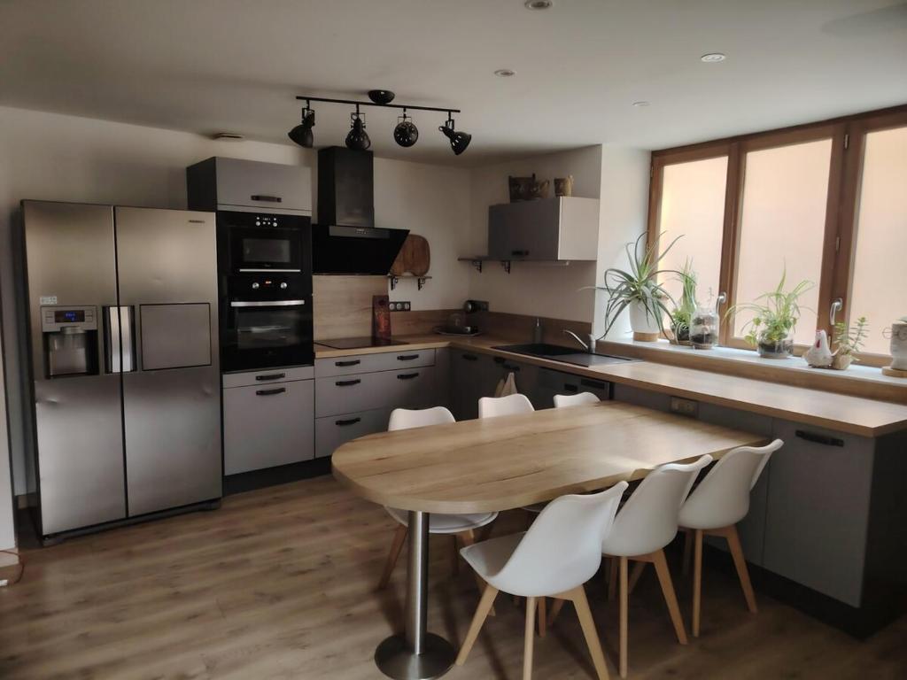 a kitchen with a wooden table and white chairs at La Casa Beaujolaise in Charnay