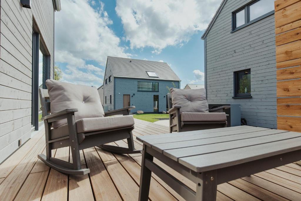 a patio with two chairs and a table on a deck at NEU "Rügen Resørt Sagard" großzügiges, gemütliches Familienhaus "Alva" mit Terrasse in Sagard