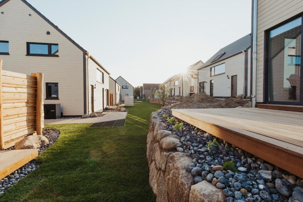 a retaining wall with a wooden deck next to a house at "Rügen Resort Sagard" großzügige, gemütliche Doppelhaushälfte "Niels" mit Terrasse in Sagard