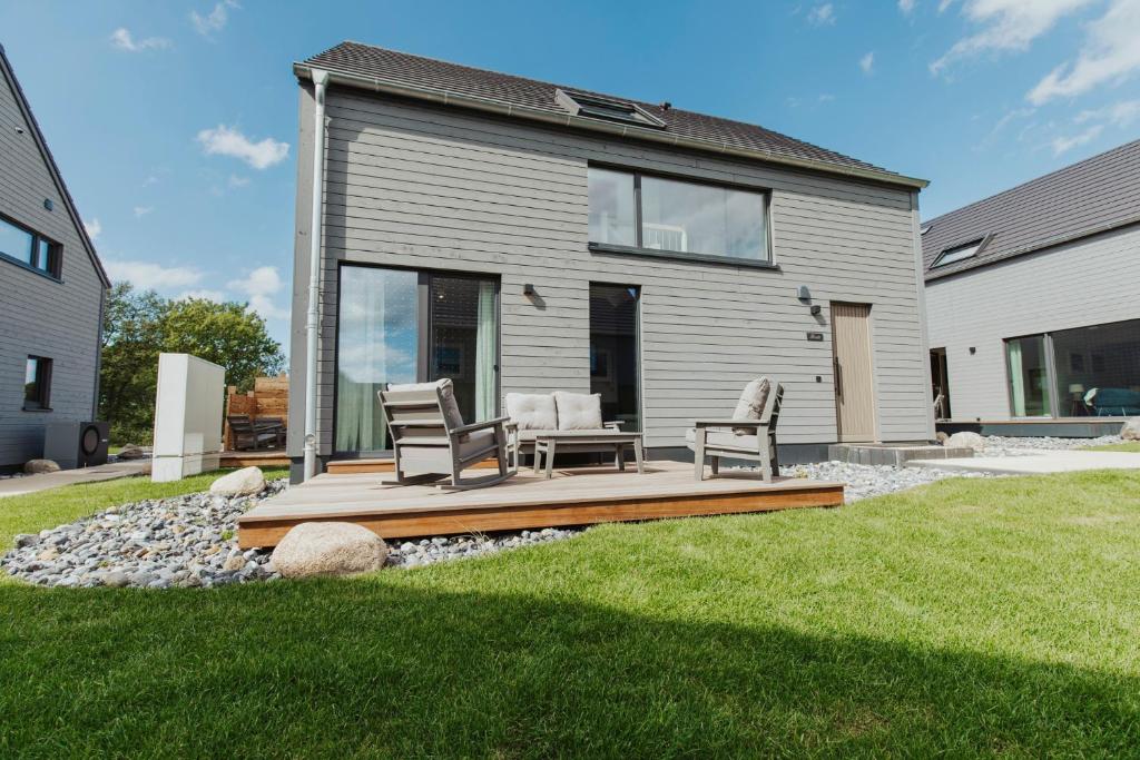a house with a deck with two chairs on it at NEU "Rügen Resørt Sagard" großzügige, gemütliche Doppelhaushälfte "Maja" mit Terrasse in Sagard