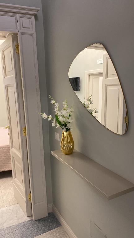 a bathroom with a mirror and a vase with flowers at La Casa Del Monsignore in Torre del Greco