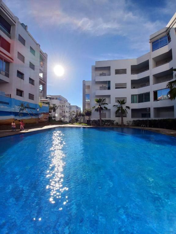 a large blue swimming pool in front of a building at La Siesta Beach Resort in Mohammedia
