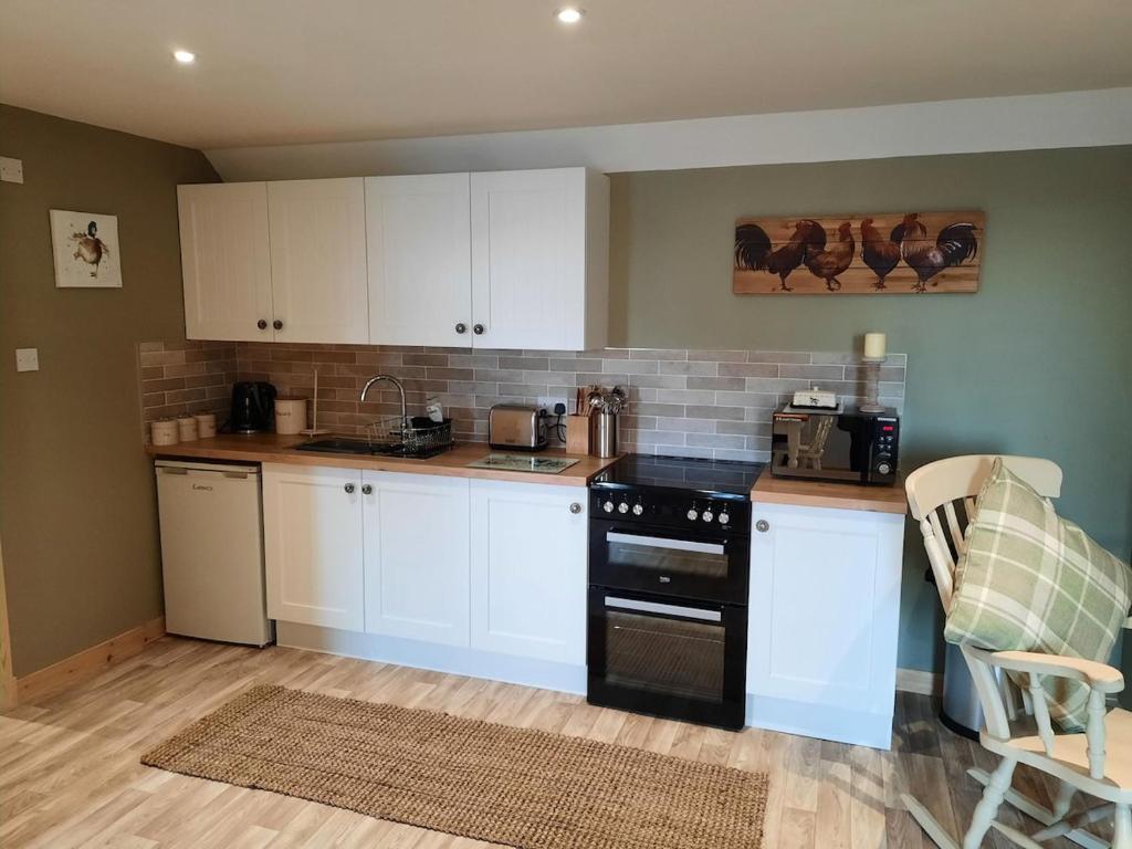 a kitchen with white cabinets and a black stove at A Stylish Country Retreat! in Keilour