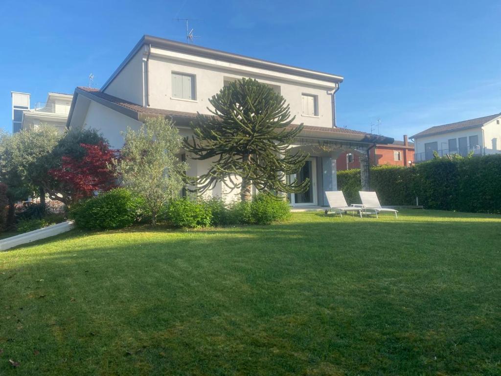 a house with two white chairs in a yard at Amazing Private Villa in Caorle