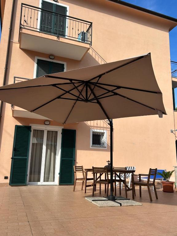 a table and chairs under an umbrella in front of a building at Appartamento Camineve 1 in Loano