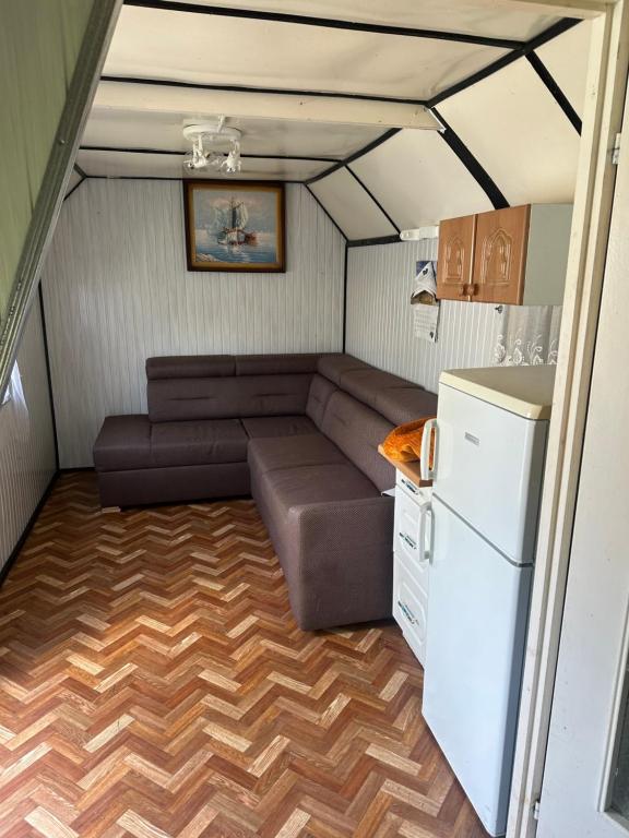 una pequeña sala de estar con sofá y nevera. en Sypialnia Rybaka, en Chwarszczany