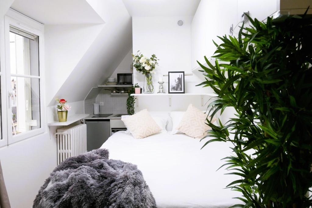 - une chambre blanche avec un lit blanc et une plante dans l'établissement Tour Eiffel - Invalides - Studio, à Paris